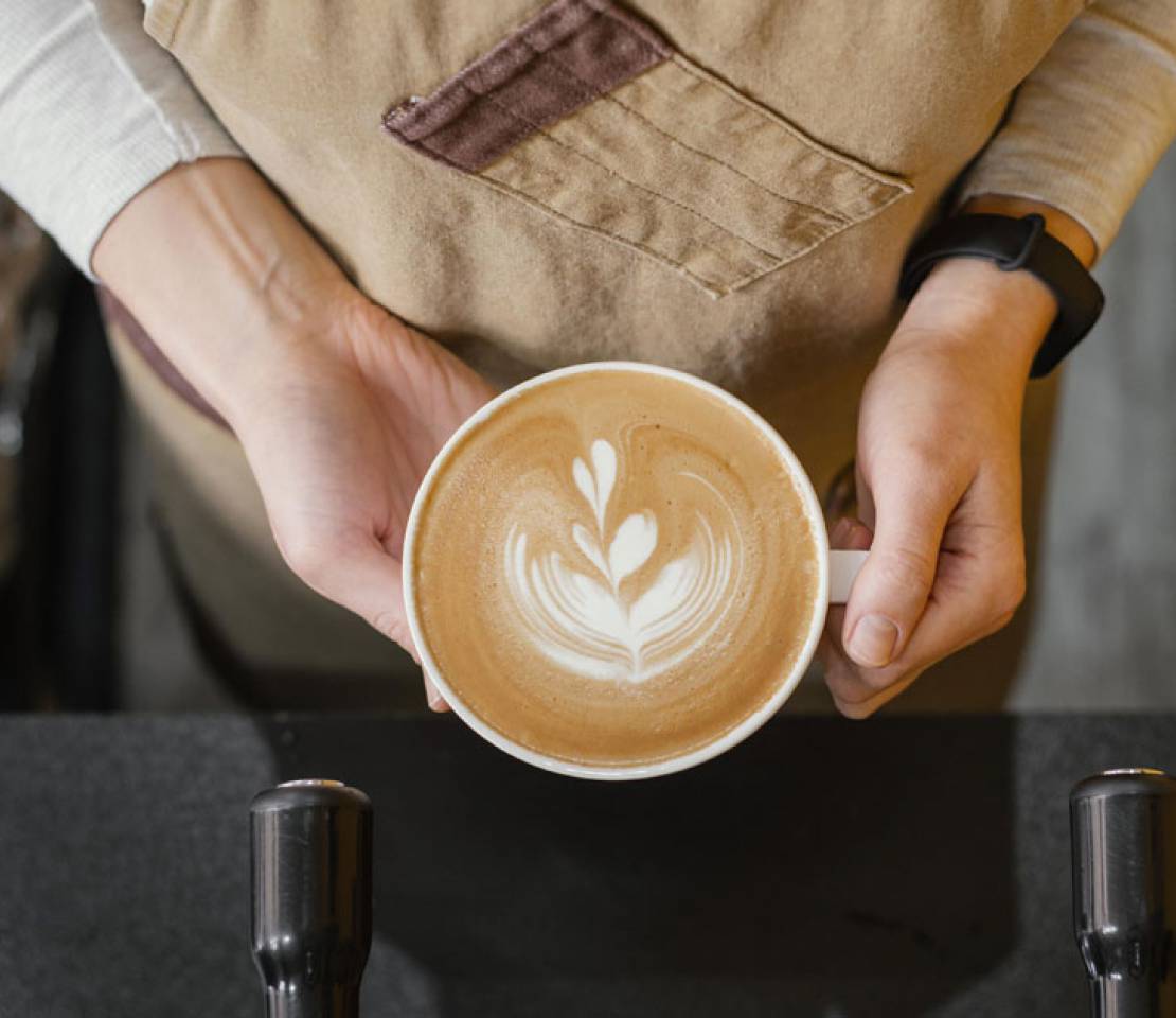 Top View of Our Female Barista Holding Cup of Coffee